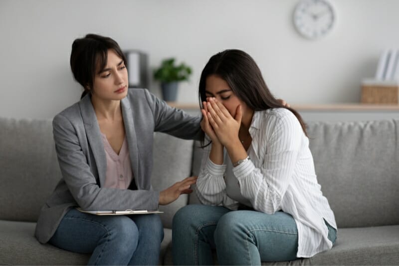 therapist working with female depression patient sitting on gray sofa in office. 